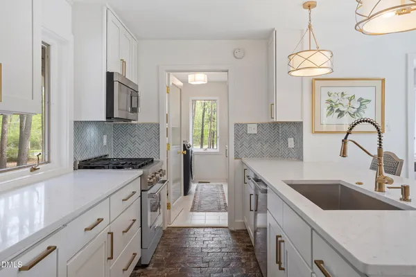 a kitchen with granite countertop a sink stainless steel appliances and window