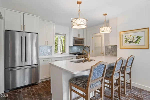 a kitchen with stainless steel appliances granite countertop a refrigerator a sink a stove a dining table and chairs