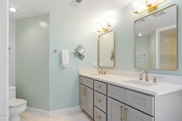 a bathroom with a double vanity sink toilet and mirror