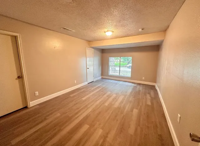 an empty room with wooden floor and windows