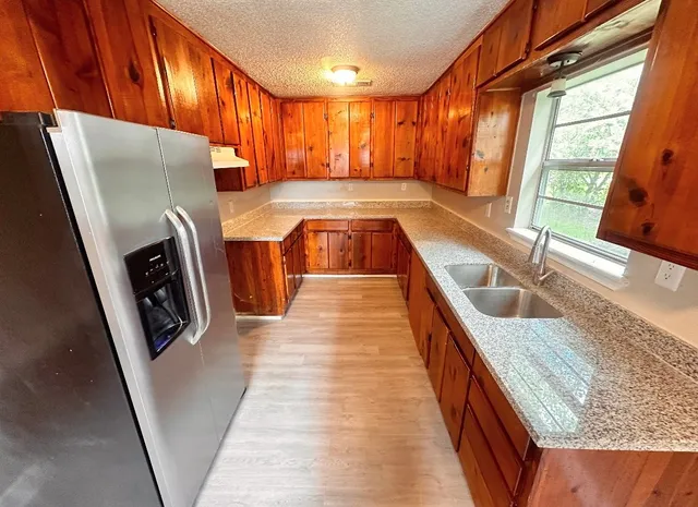 a kitchen with stainless steel appliances granite countertop a refrigerator a sink a stove top oven and a dishwasher