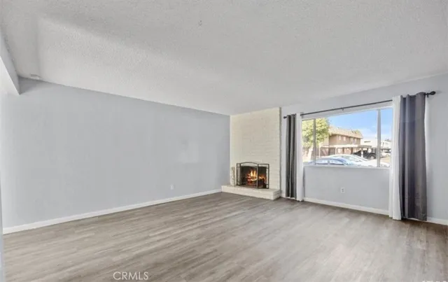 an empty room with wooden floor and fireplace