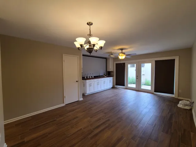 a view of a big room with wooden floor a chandelier and entryway