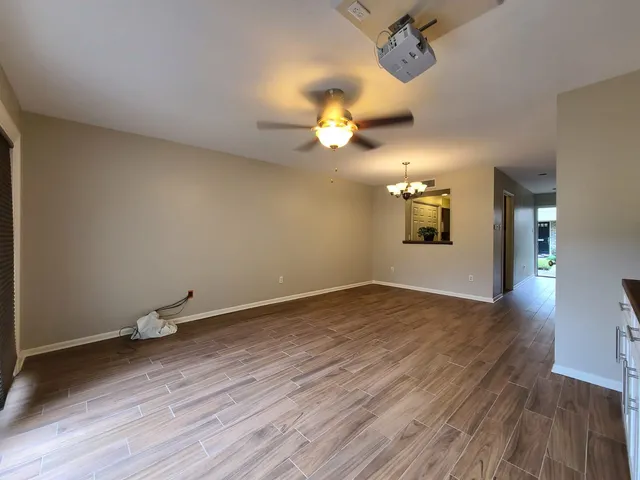 a view of an empty room with a window and wooden floor