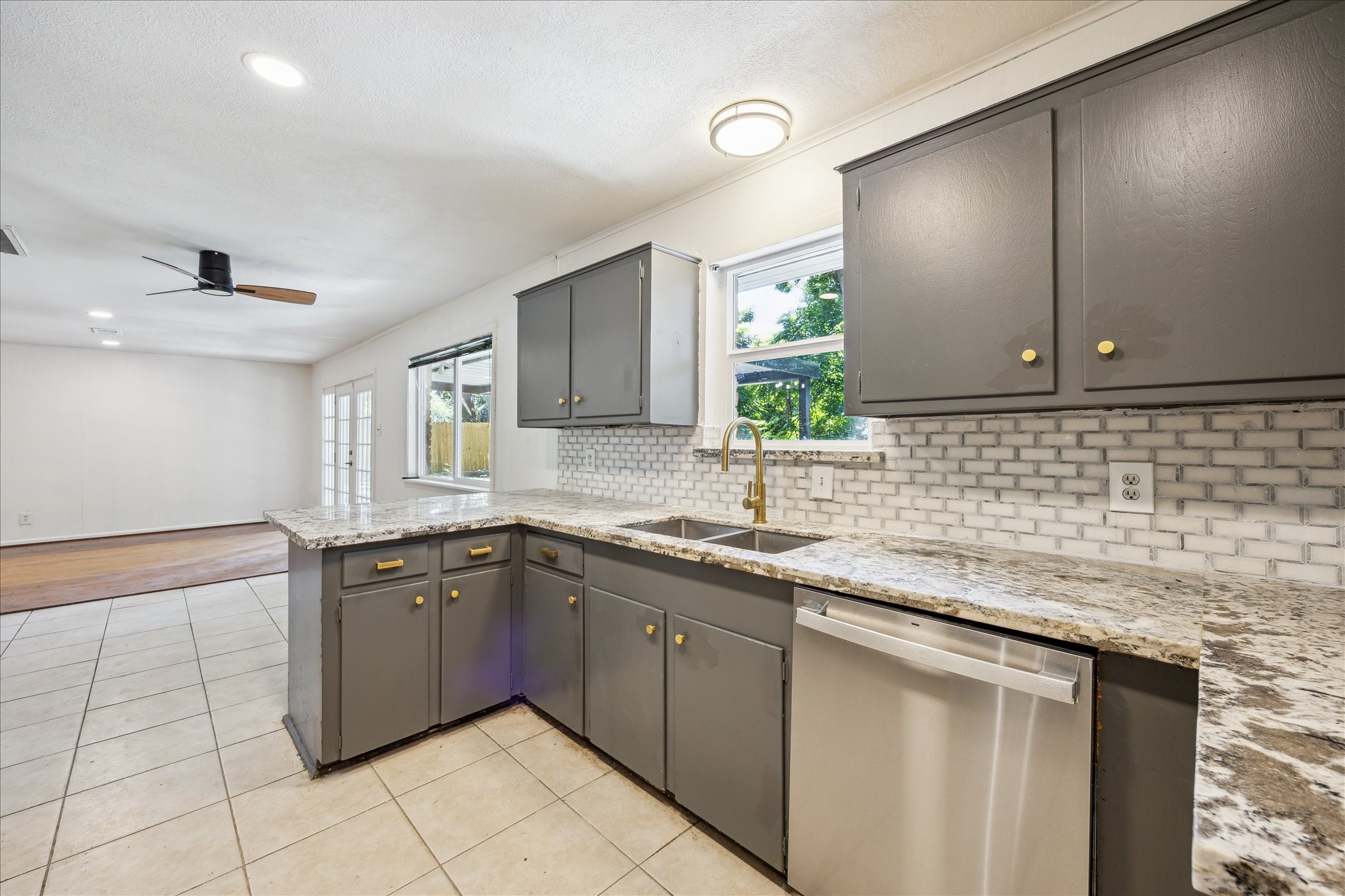 5419 Beechnut Street Houston, TX 77096 - Photo 11 of 28 Granite countertops with subway tile backsplash, double sink, and window overlooking the backyard, open to the den.