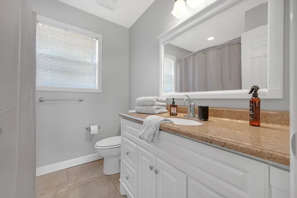 a bathroom with a granite countertop sink a toilet and a window