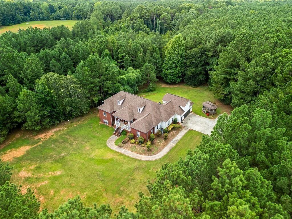 an aerial view of a house with swimming pool big yard and large trees