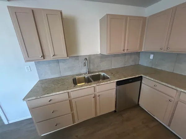 a kitchen with granite countertop white cabinets and sink