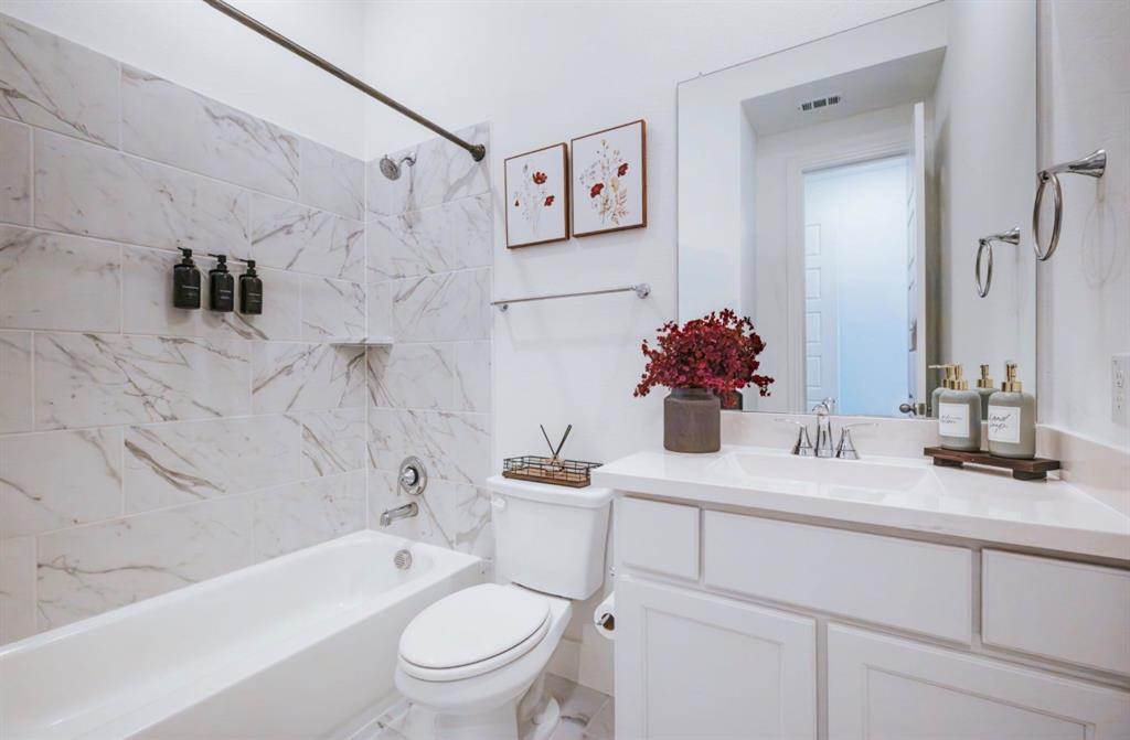 2150 Charming Frg Road Forney, TX 75126 - Photo 21 of 40 White tile flooring, white vanity with integrated sink and chrome fixtures, white toilet, white bathtub with a bronze shower rod, and white tiled shower surround