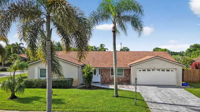 a view of a house with a yard and palm trees
