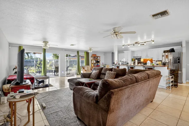 a living room with furniture kitchen view and large windows