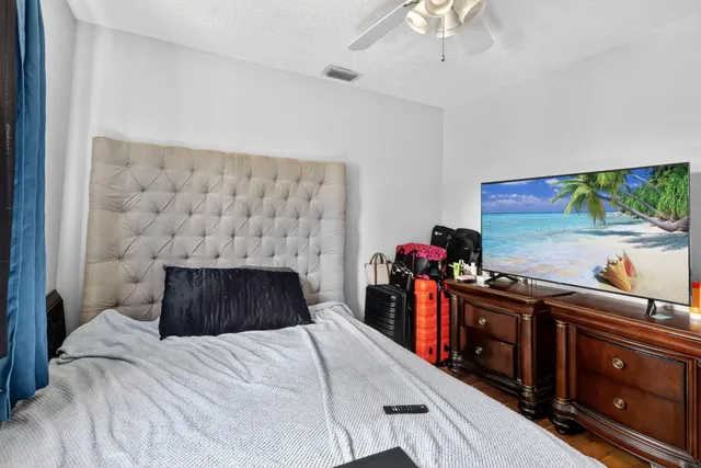 a bedroom with a bed and a flat tv screen on dresser
