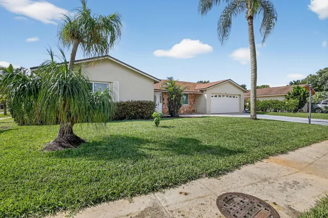 a view of a house with a yard and palm trees