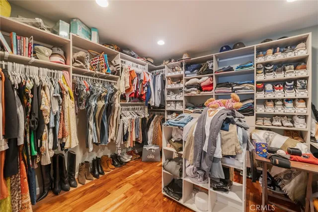 a view of walk in closet with clothes and shoes