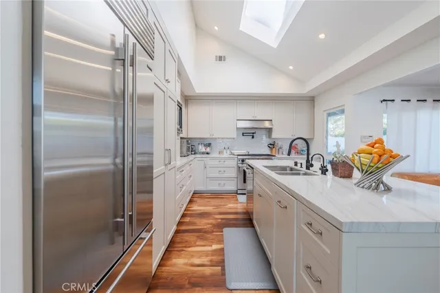 a kitchen with stainless steel appliances granite countertop a sink and a refrigerator