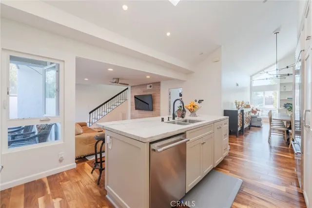 a large white kitchen with wooden floor and a sink