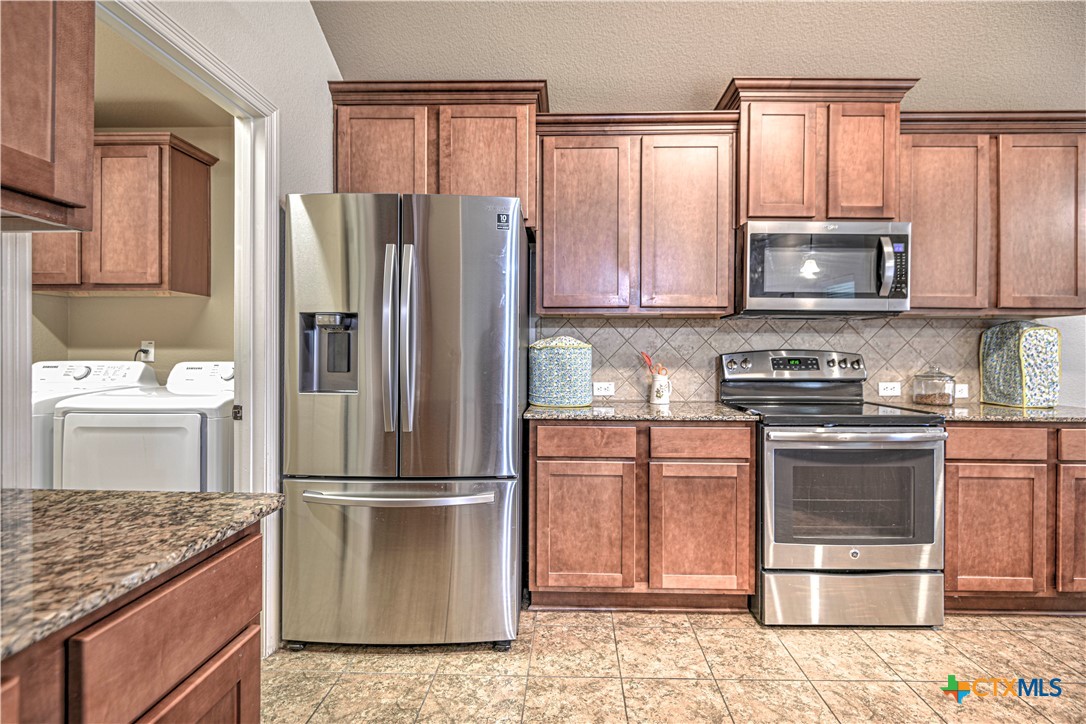 8405 Split Trl Cove Temple, TX 76502 - Photo 16 of 37 a kitchen with granite countertop a refrigerator stove and microwave