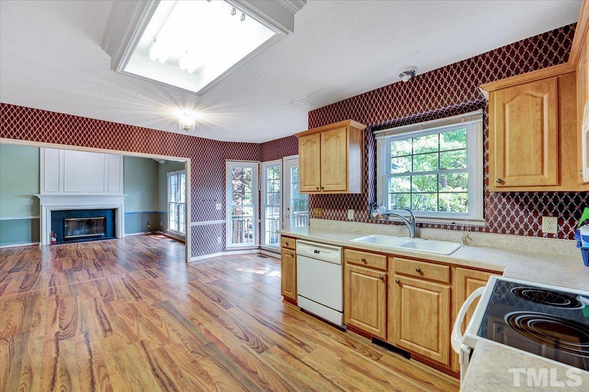 4003 Kettering Drive Durham, NC 27713 - Photo 7 of 28 a large kitchen with kitchen island granite countertop a stove a sink dishwasher and white cabinets with wooden floor