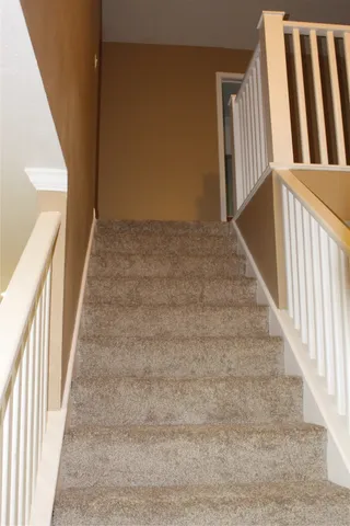 a view of staircase with railing and a rug
