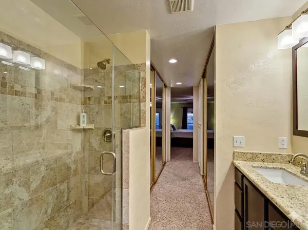 a bathroom with a granite countertop shower a sink and a mirror