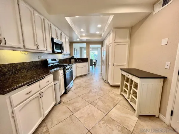 a kitchen with stainless steel appliances granite countertop a stove a sink and a microwave
