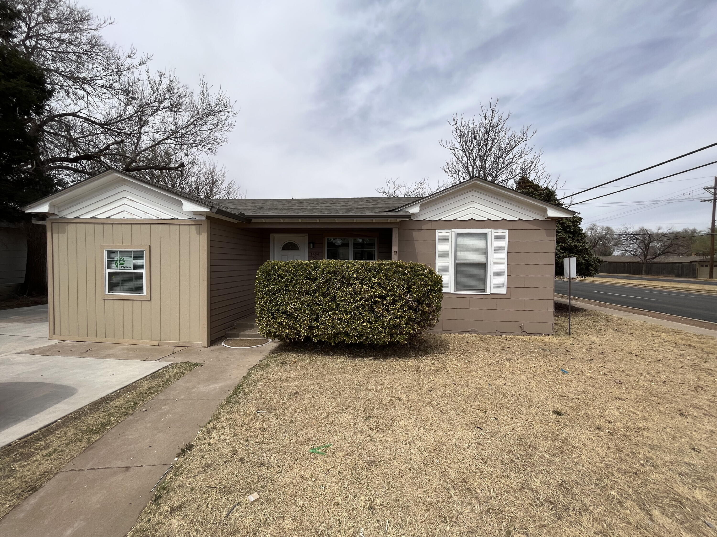 3404 30th Street Lubbock, TX 79410 - Photo 1 of 13 a front view of a house with a garden and garage