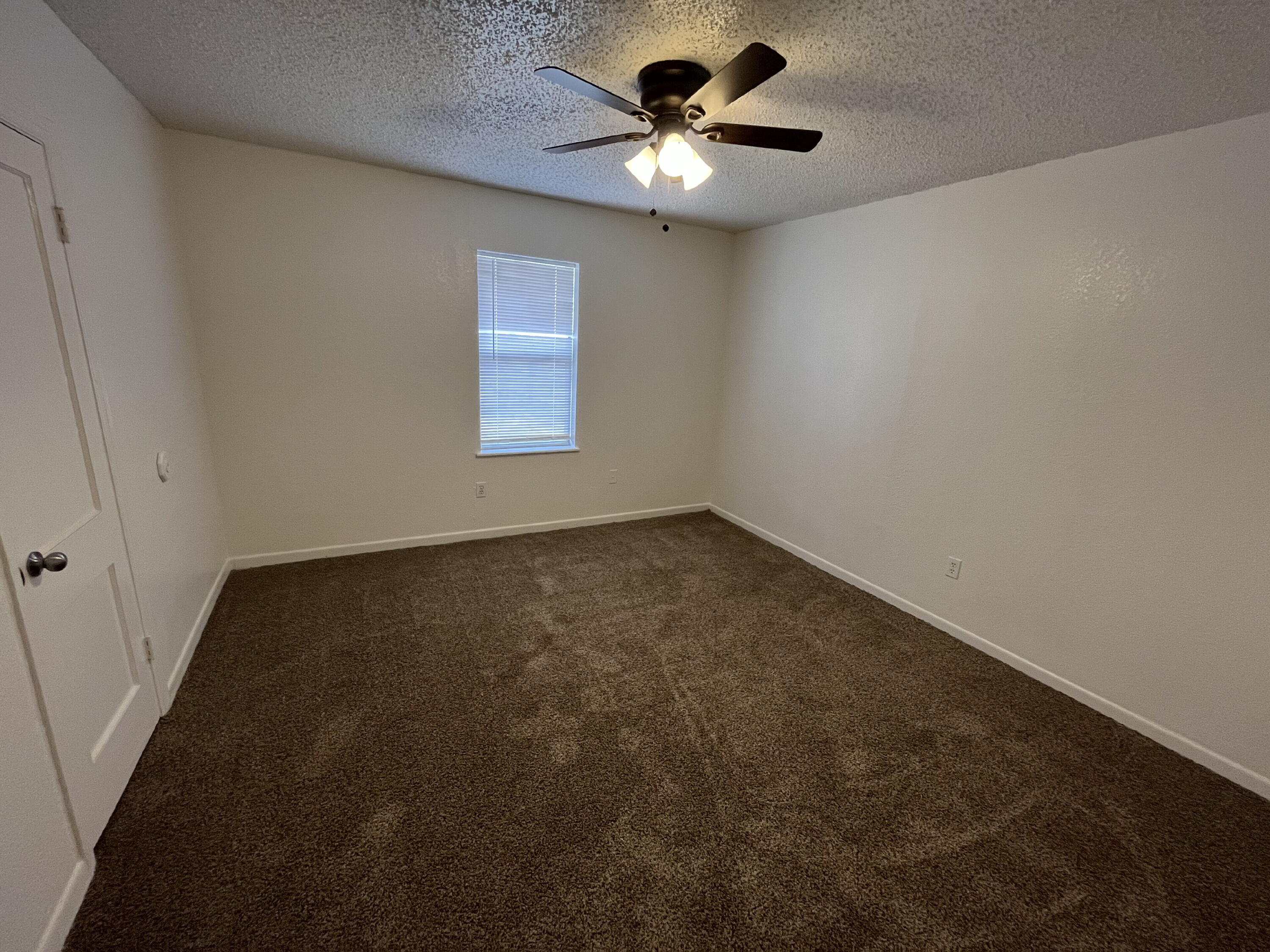 3404 30th Street Lubbock, TX 79410 - Photo 10 of 13 an empty room with a chandelier fan and windows
