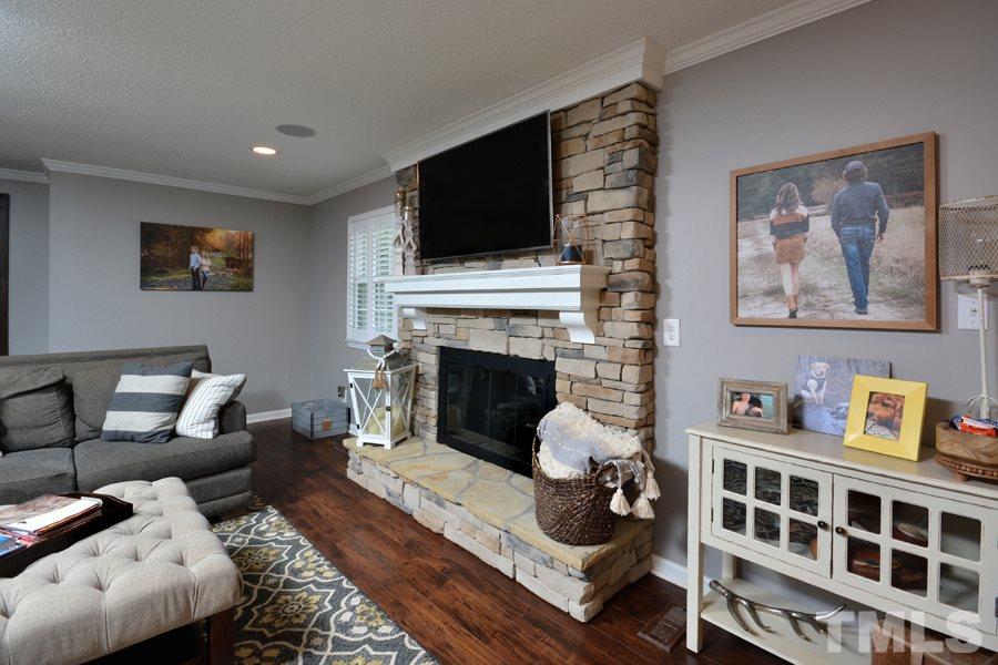 2260 Sanders Road Stem, NC 27581 - Photo 12 of 30 a living room with furniture a flat screen tv and a fireplace