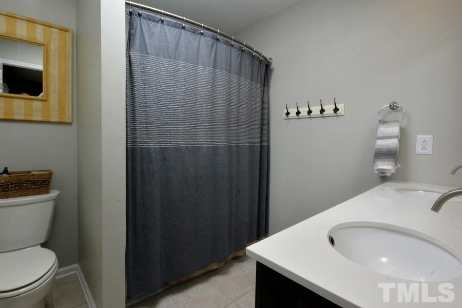 2260 Sanders Road Stem, NC 27581 - Photo 17 of 30 a bathroom with a sink a toilet and shower curtain