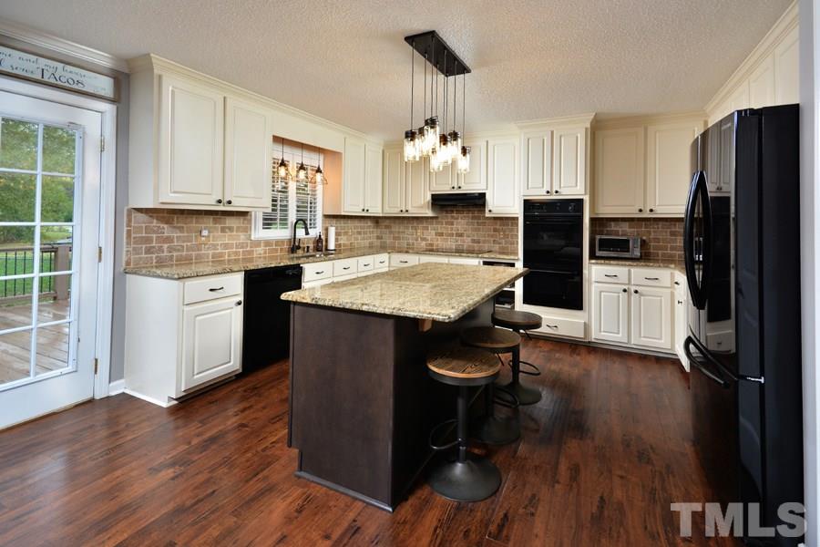 2260 Sanders Road Stem, NC 27581 - Photo 7 of 30 a kitchen with granite countertop kitchen island wooden floors cabinets a counter and appliances