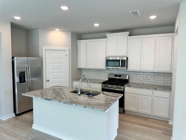 a kitchen with stainless steel appliances granite countertop a stove a sink and a refrigerator