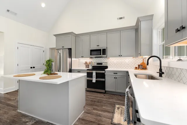 a kitchen with refrigerator a stove a sink and white cabinets with wooden floor