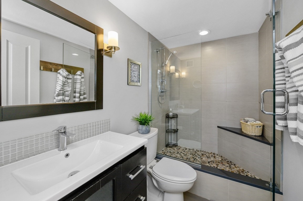 8-12 Museum Way, Unit 828 Cambridge, MA 02141 - Photo 9 of 13 a bathroom with a sink a toilet a mirror and shower