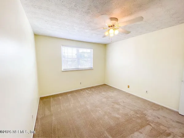 an empty room with a ceiling fan and a window