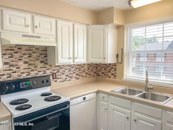 a kitchen with granite countertop a sink stove and cabinets