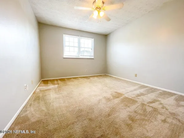 an empty room with a chandelier fan and windows