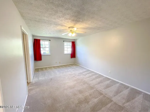 an empty room with windows and fan