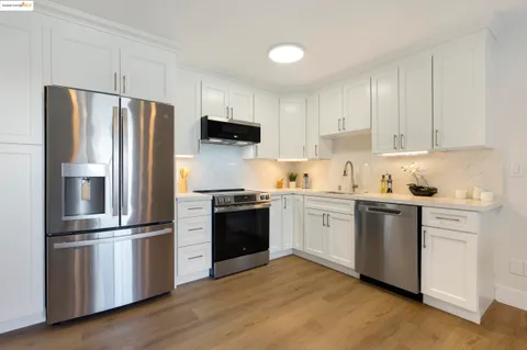 a kitchen with granite countertop white cabinets and stainless steel appliances