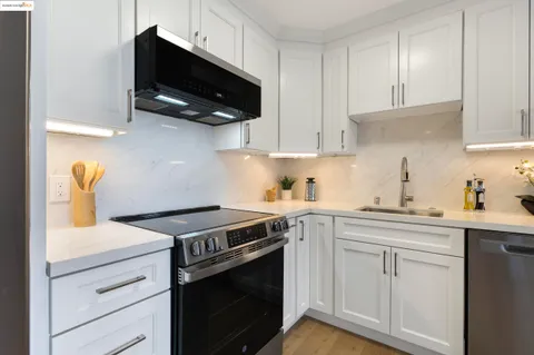 a kitchen with stainless steel appliances white cabinets and a stove top oven