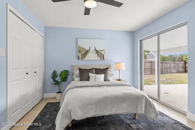 a bedroom with a bed painting on wall and a large window