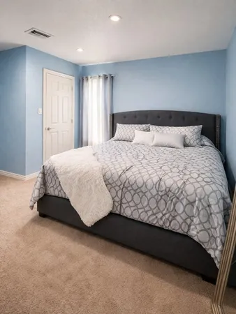 a large bed sitting in a bedroom next to a window