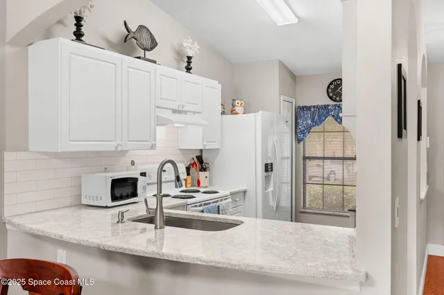 a kitchen with stainless steel appliances granite countertop a sink and a refrigerator