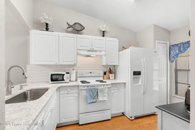 a kitchen with white cabinets sink and white appliances