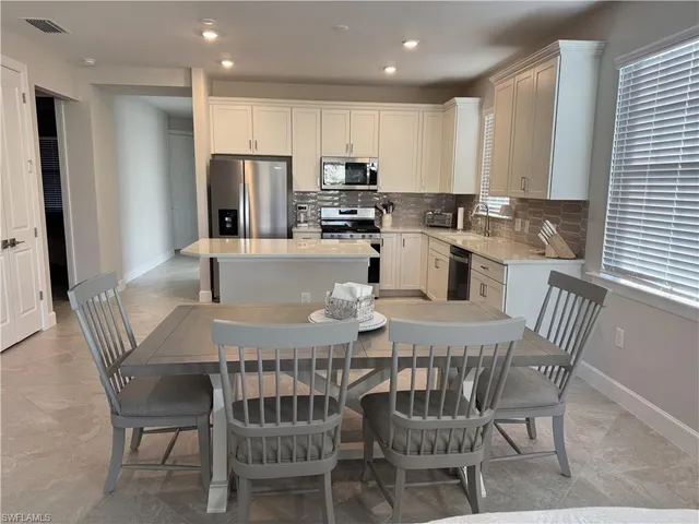 a kitchen with a dining table chairs and refrigerator