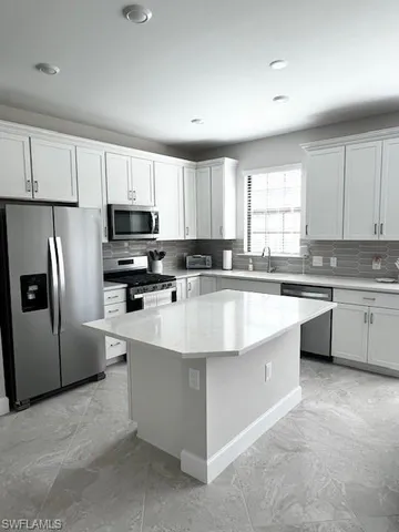 a kitchen with stainless steel appliances granite countertop a sink a stove a refrigerator a center island and a window