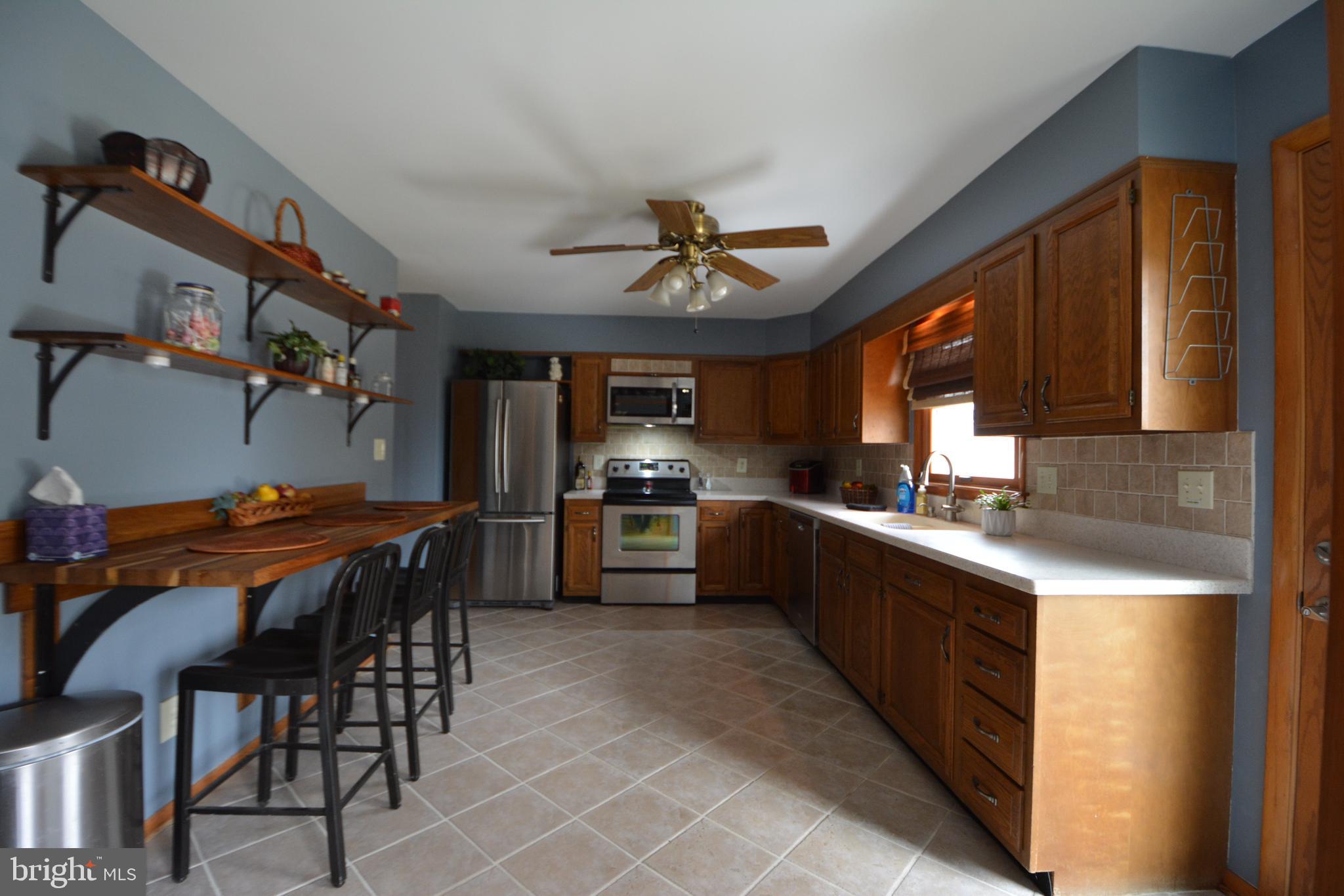 1658 Sams Creek Road Westminster, MD 21157 - Photo 5 of 59 a kitchen with stainless steel appliances a table chairs and a refrigerator