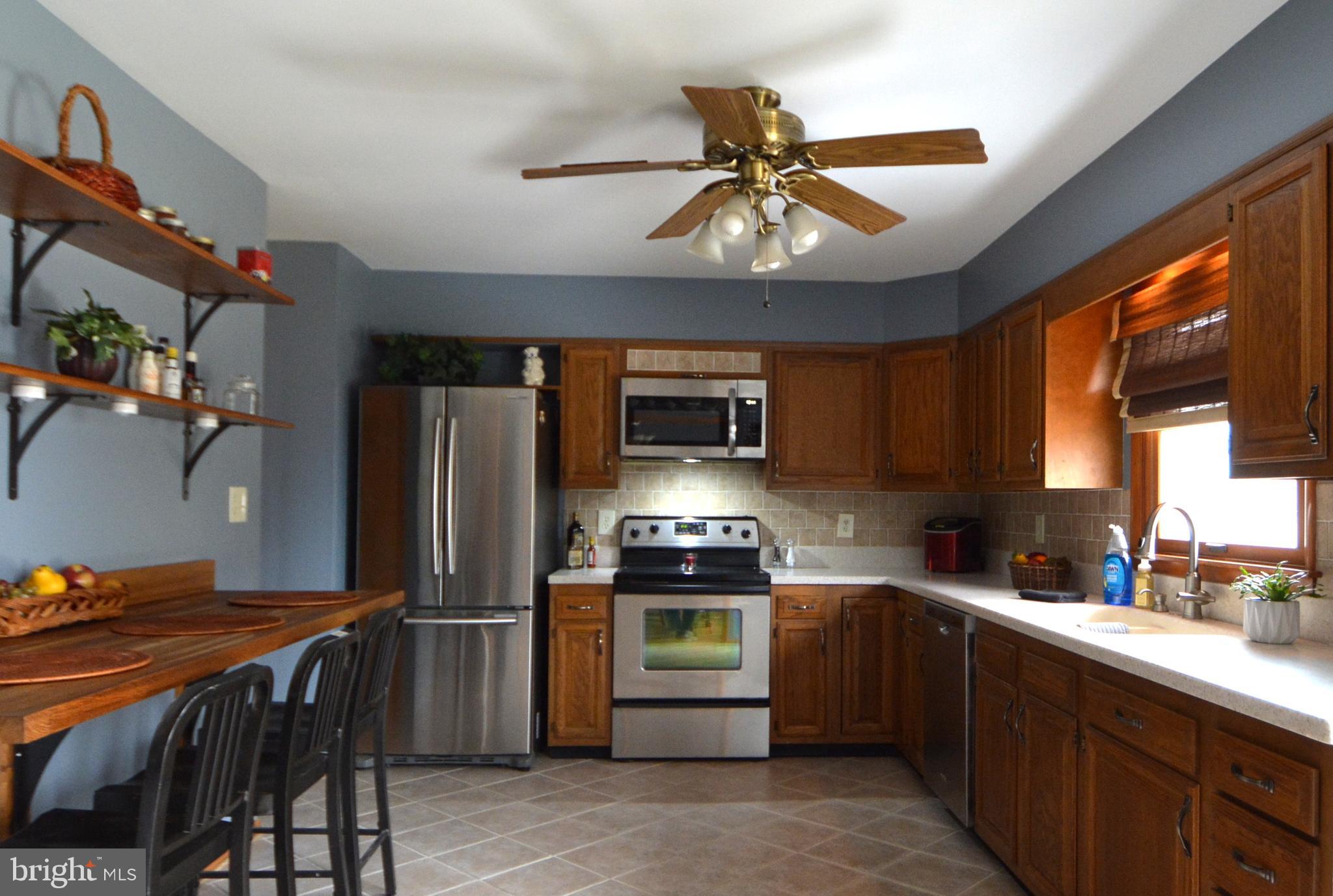 1658 Sams Creek Road Westminster, MD 21157 - Photo 9 of 59 a kitchen with stainless steel appliances a table chairs and a refrigerator