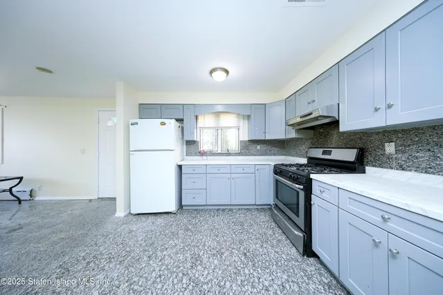 a kitchen with a sink a stove a refrigerator and white cabinets