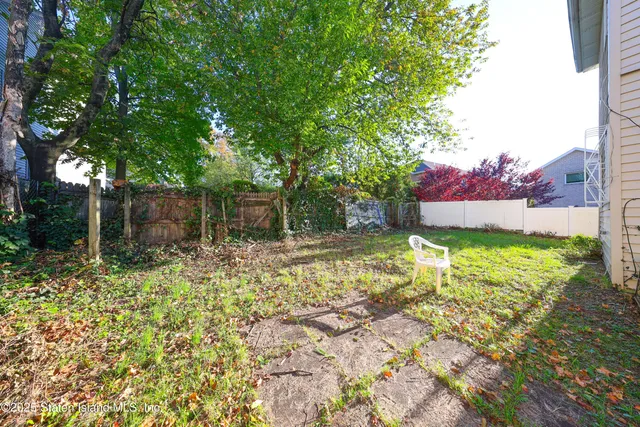 a view of a backyard with table and chairs and wooden fence