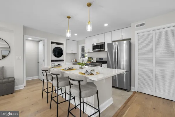 a kitchen with a dining table cabinets appliances and wooden floor